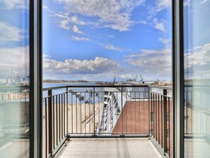 A balcony with a view of a port and a brick building.