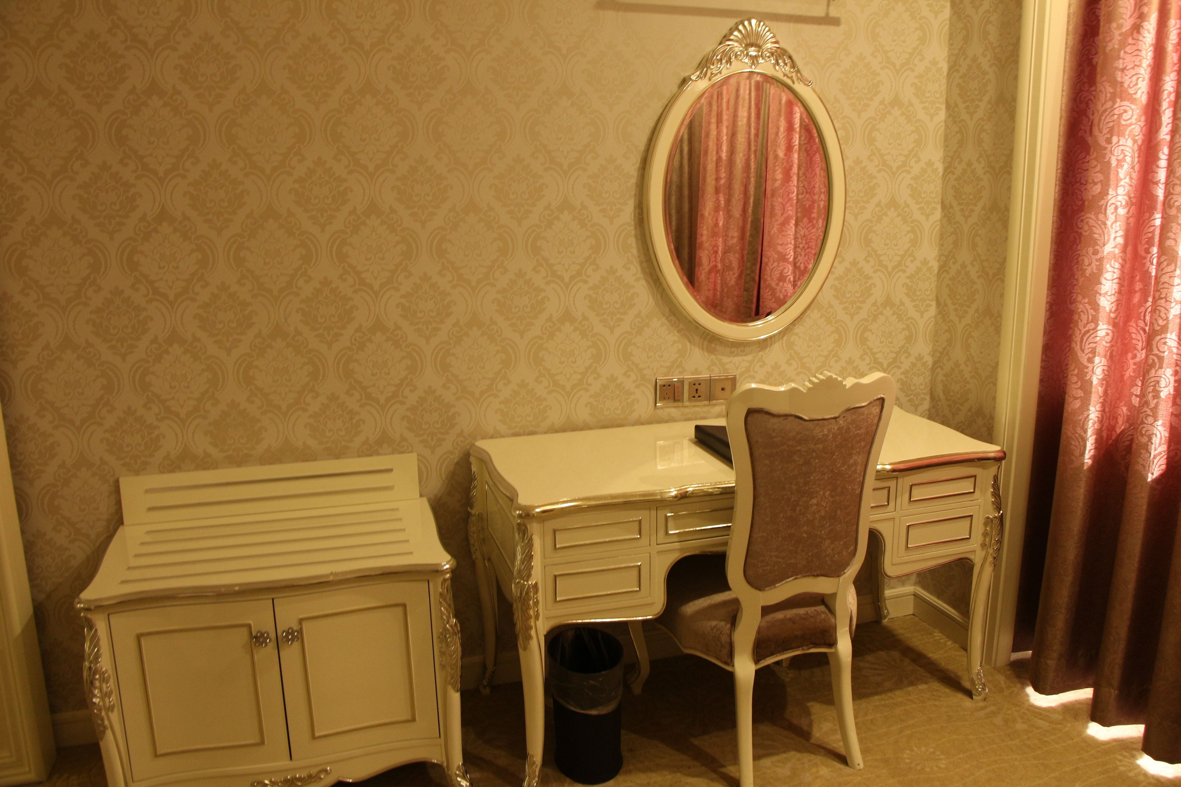 Une pièce comprenant une coiffeuse blanche, un miroir, une chaise et un meuble de rangement.