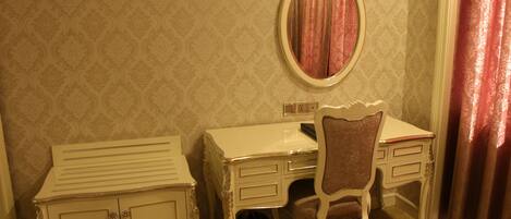 Une pièce comprenant une coiffeuse blanche, un miroir, une chaise et un meuble de rangement.