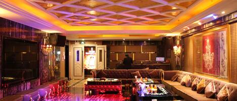 A luxurious lobby with a bar area, seating, and a television screen.