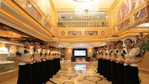 A grand hall with a chandelier, a stage, and a group of people in formal attire. - Zhuhai Rongfeng Hotel (Zhuhai)