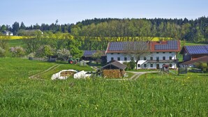 Ein Landhaus mit Solaranlage, umgeben von grünen Feldern und Bäumen.