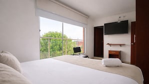 A hotel room with a large bed, a chair, a TV, and a balcony with a view. - Hotel Dorado Gold Bogota (Bogotá)