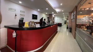 A reception area with a curved red counter, a digital screen, and a clock on the wall. - Hotel Dorado Gold Bogota (Bogotá)