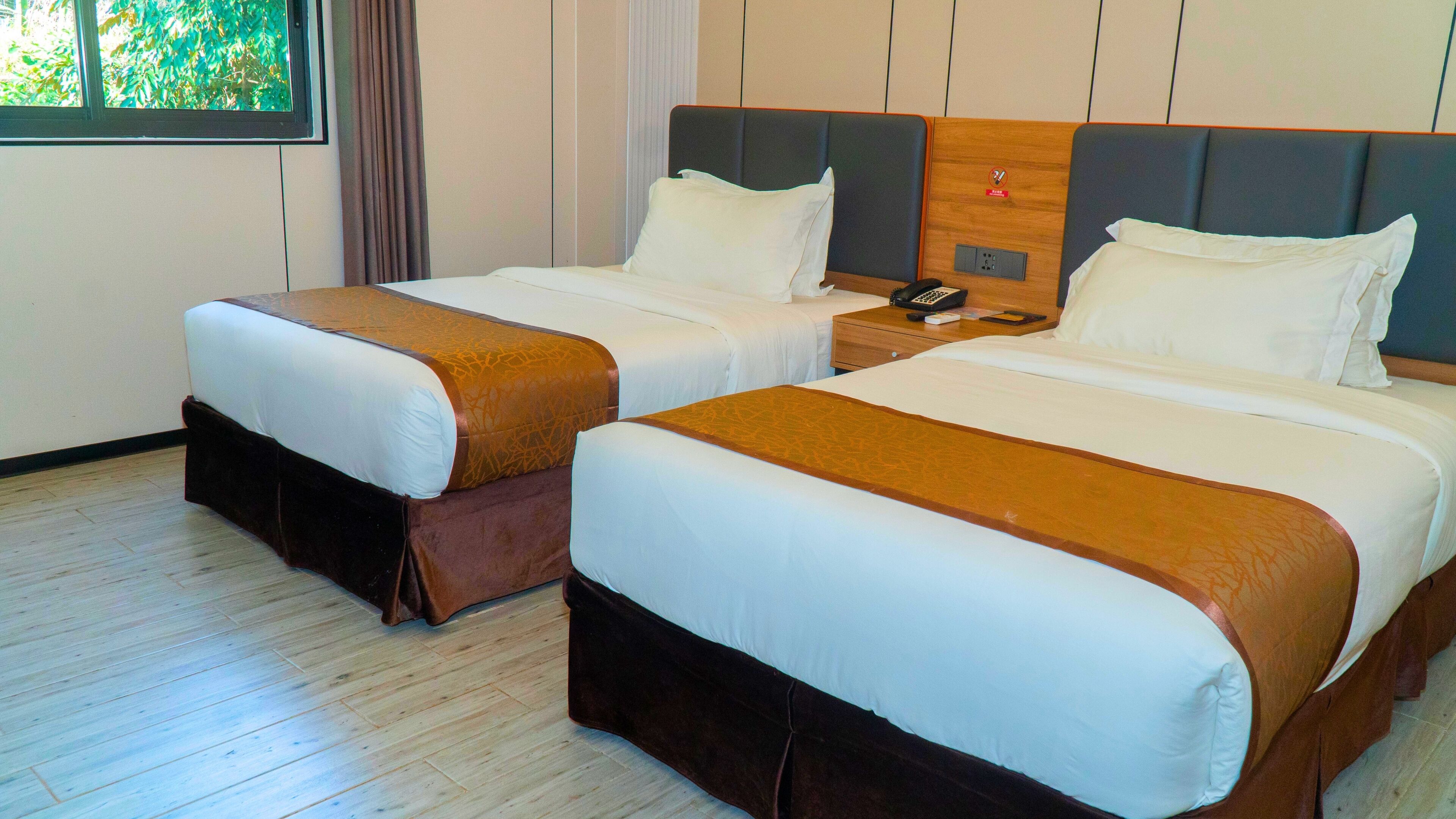 Two double beds with brown headboards and white bedding in a hotel room.