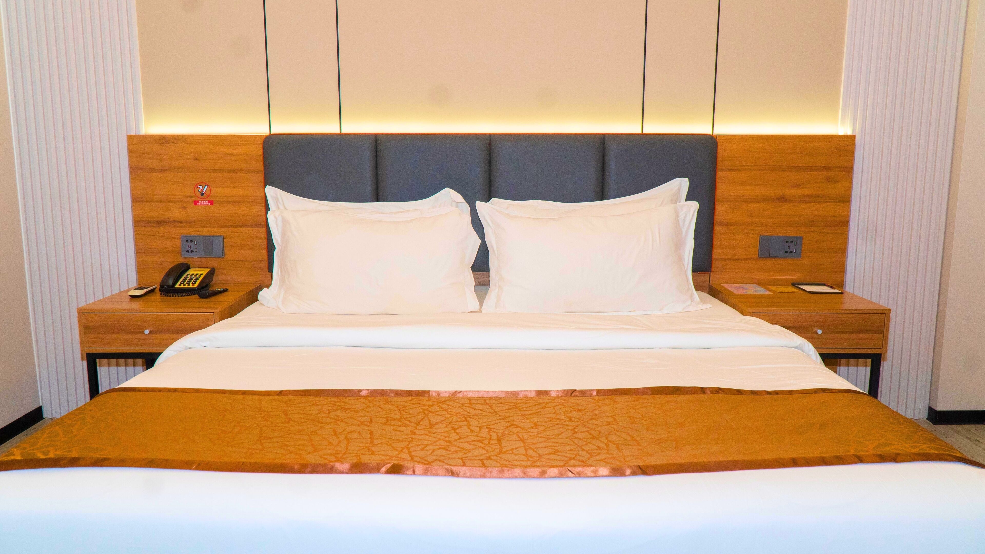 Ein Hotelzimmer mit einem großen Bett, zwei Nachttischen, einem Telefon und einer Wandleuchte.