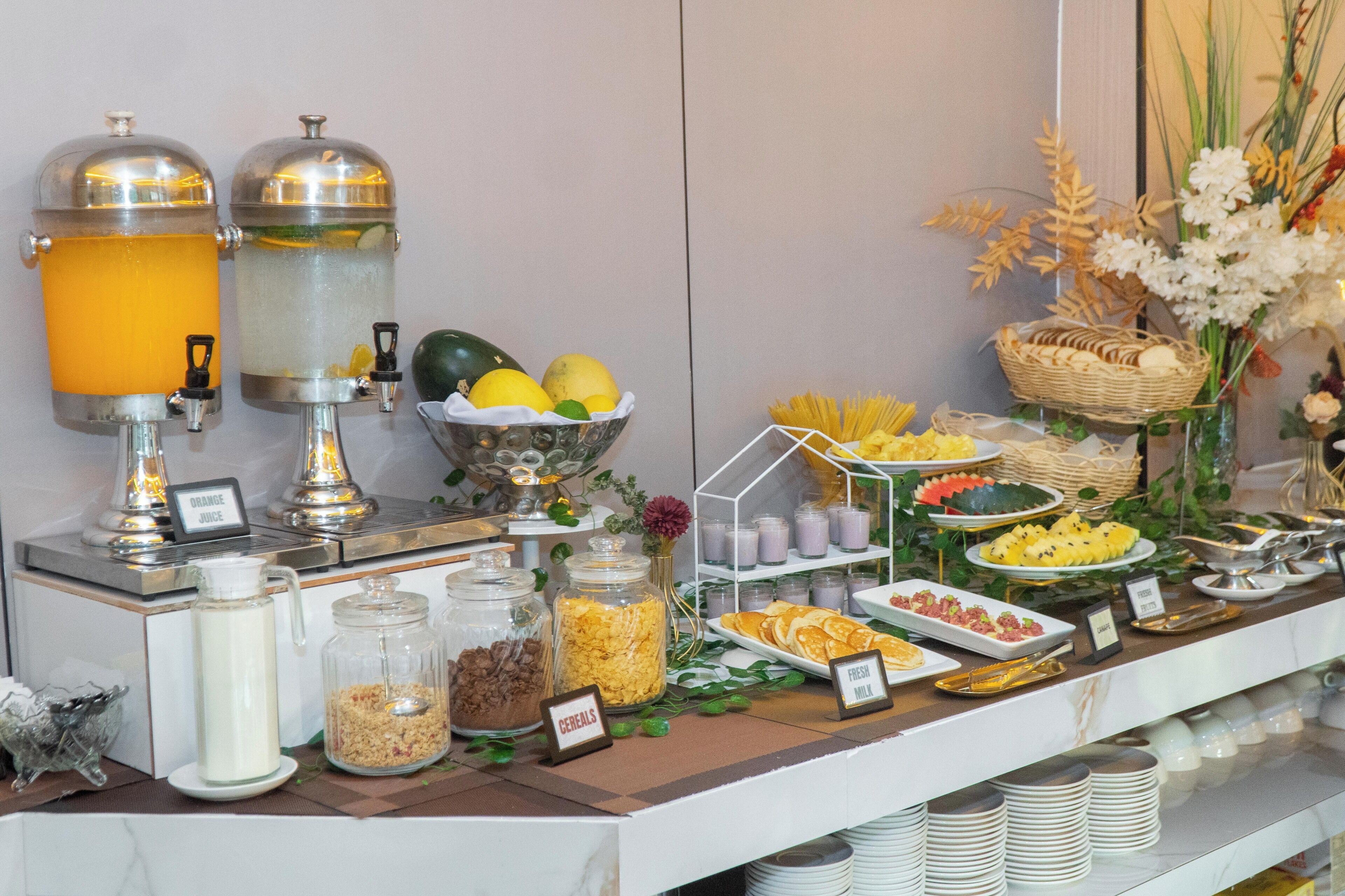 A buffet with various food items, including fruits, cereals, and dairy products.
