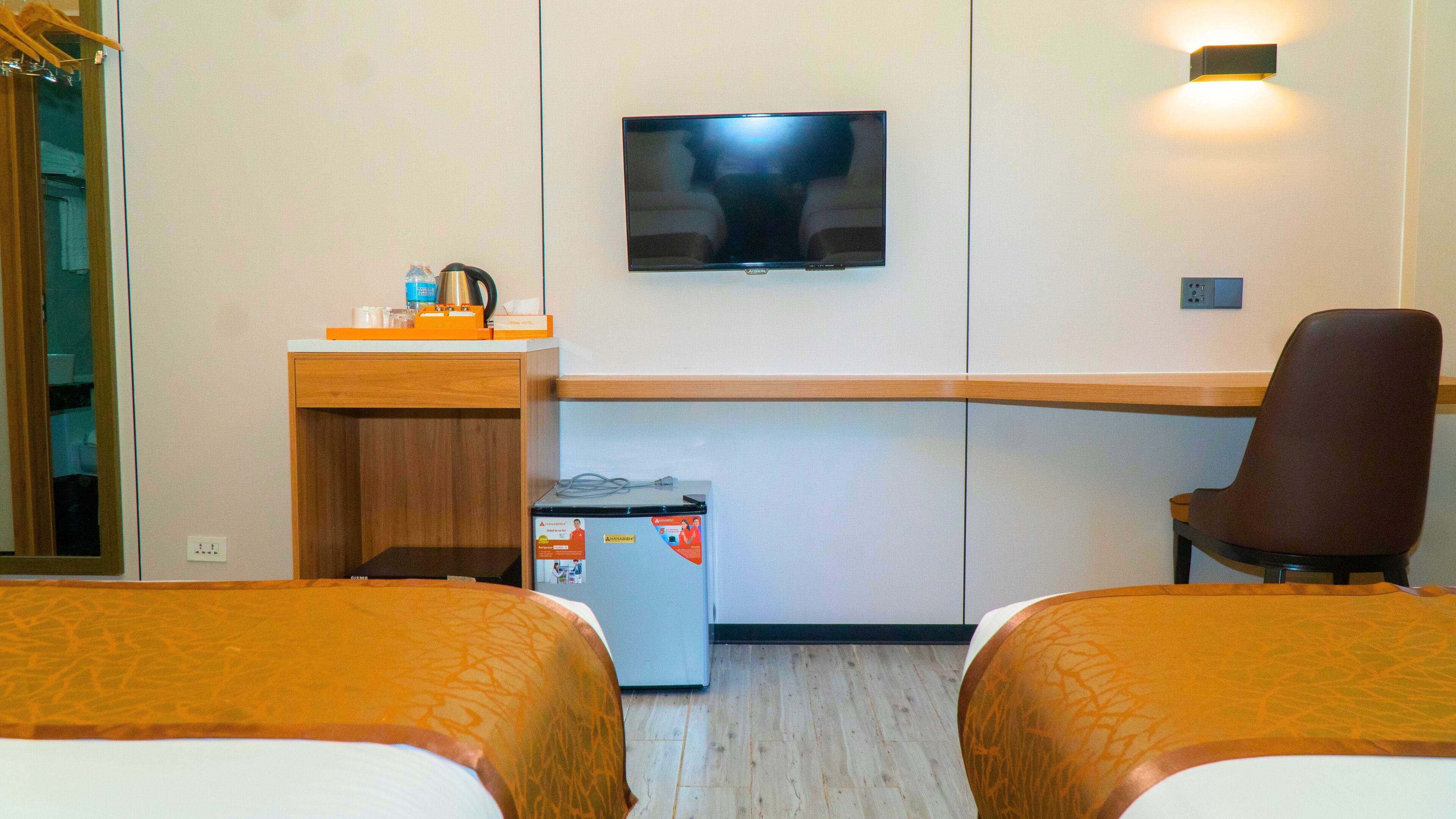 Habitación de hotel con dos camas, un escritorio, televisor y minibar.