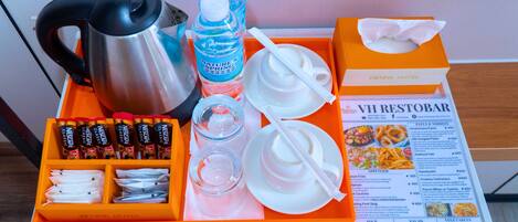 A hotel room's breakfast tray with a coffee maker, Nescafe Classic coffee packets, a water bottle, a glass, a napkin, and a menu.