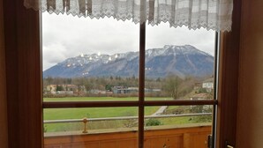A balcony with a wooden railing, a bench, and a view of a mountain range. - Ferienwohnung Bergstation im Dopplerhof 2.OG 100qm, 2 Schlafzimmer (Piding)
