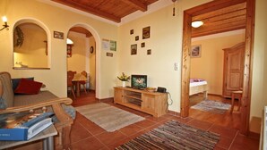Ein gemütliches Wohnzimmer mit einer Holzunterhaltungsecke, einer Couch und einem Essbereich mit Tisch und Stühlen.