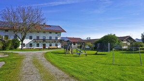 Ein weißes Gebäude mit rotem Dach, einem Kiesweg und einer Rasenfläche mit einer Schaukel.