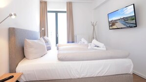 Ein Hotelzimmer mit Bett, Fernseher und Blick auf die Stadt.