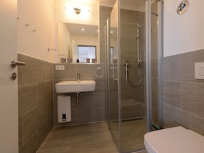 Ein modernes Badezimmer mit einer Duschkabine, einem Waschbecken und einer Toilette.