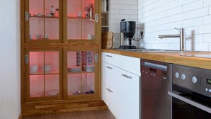 A modern kitchen with white cabinets, a wooden cabinet with glass doors, a coffee maker, and a dishwasher.