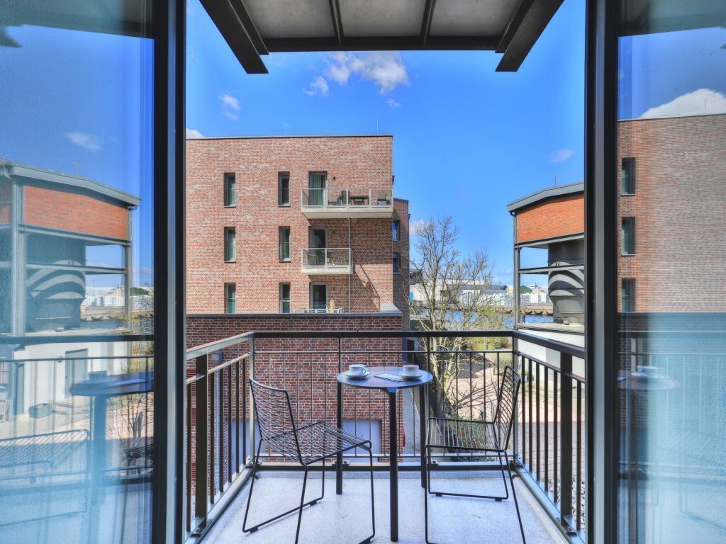 A balcony with a table and chairs, overlooking a brick building with multiple windows and balconies.