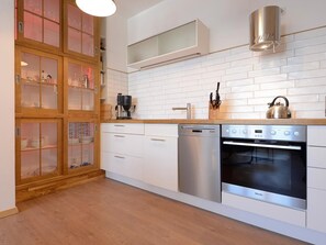 Una cocina moderna con armarios blancos, un lavavajillas de acero inoxidable, un horno y una encimera de madera.