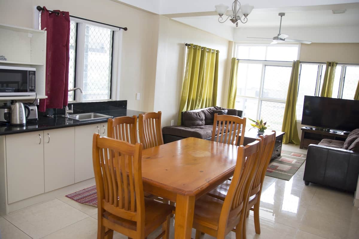 A modern kitchen with a microwave, sink, and dining area with wooden chairs.