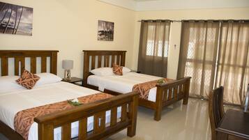 A hotel room with two wooden beds, a small table, and a chair.