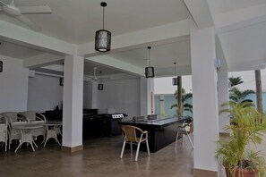 A spacious indoor area with a central kitchen island, seating arrangements, and hanging pendant lights. - Samoana Boutique Hotel (Apia)