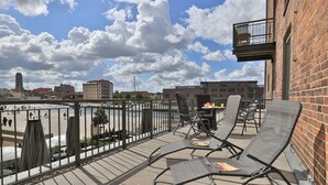 Un balcone con posti a sedere all'aperto, vista su un fiume e edifici sullo sfondo.