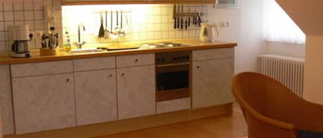 Una cocina con encimera de madera, horno empotrado y una silla.