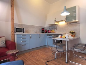 A compact kitchen with a microwave, coffee maker, and a small dining area with two chairs and a table.