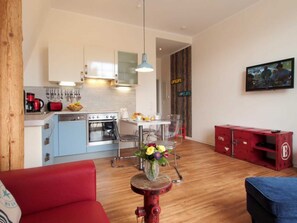 A compact kitchen with modern appliances, a dining area with a table and chairs, and a red cabinet.
