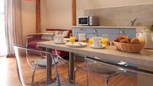 A modern kitchen with a dining area, featuring a breakfast setup with coffee, juice, and pastries. - Muschel Whg. Krabbe, Germany (Ostseebad Boltenhagen)