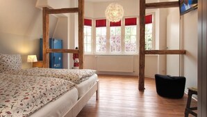 A bedroom with a large bed, wooden beams, a window with red shutters, and a hanging light fixture. - Muschel Whg. Krabbe, Germany (Ostseebad Boltenhagen)