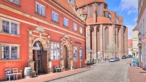 A historic building with a red facade and a church with a red roof.