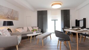 A modern living room with a sofa, a dining table, and a TV.