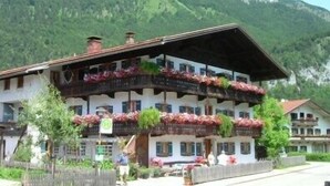 A traditional chalet-style building with multiple balconies, surrounded by lush greenery and mountains. - Apartment Geigelstein for 2 pers., 36 sqm, balcony (Schleching)