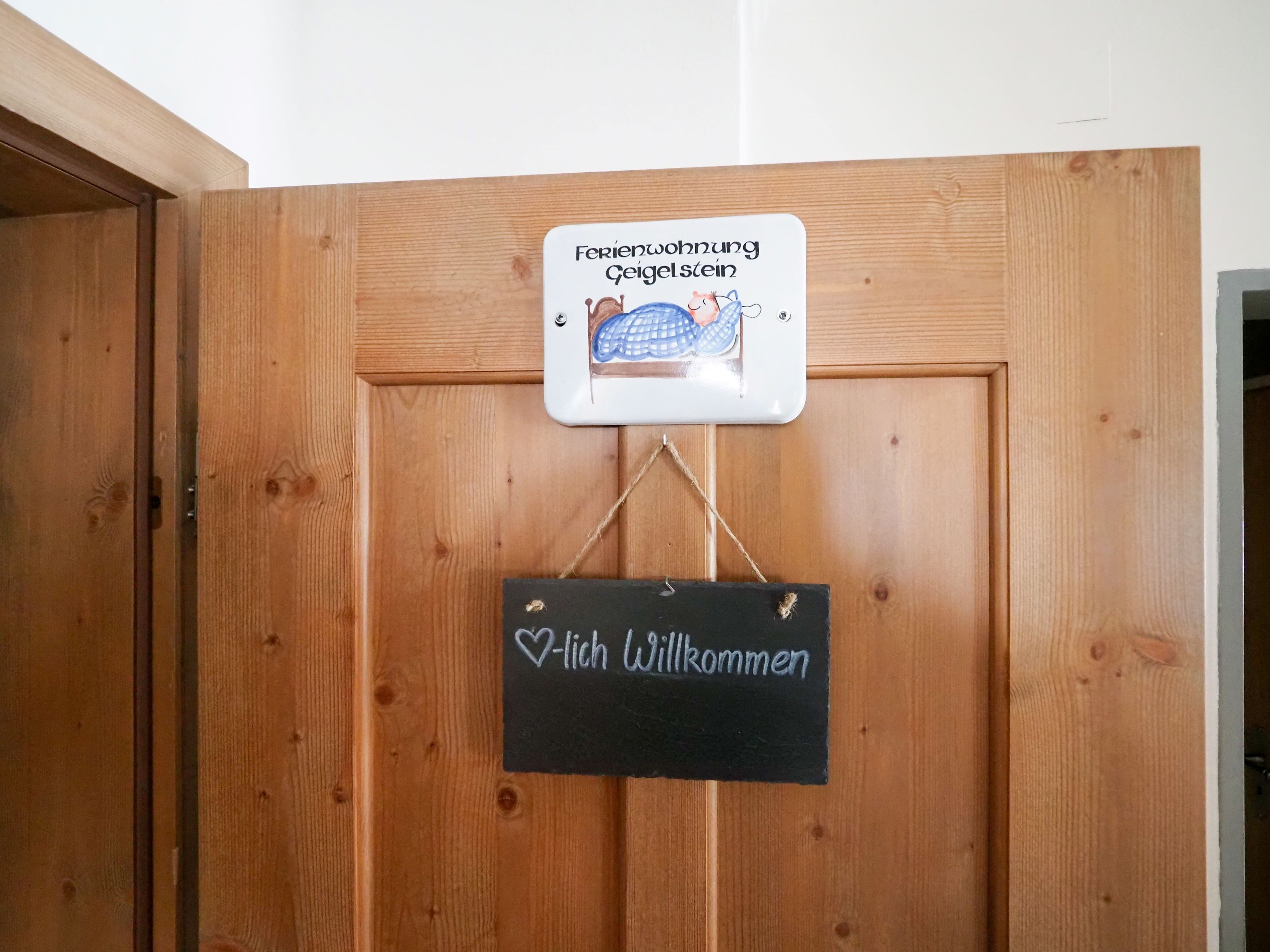 Une porte en bois avec une pancarte indiquant « Bienvenue » et une autre précisant qu’il s’agit d’une chambre adaptée aux familles.