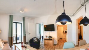Ein modernes Wohnzimmer mit einer Couch, einem Couchtisch und einem an der Wand befestigten Fernseher.