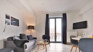 Un salon moderne avec un canapé, une table basse, un téléviseur et une vue sur le balcon.