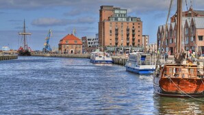 Un port avec des bateaux, un bâtiment à toit rouge et une haute structure équipée de grues.