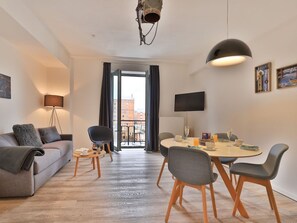 Un salon moderne avec un canapé, des fauteuils, une table à manger et un téléviseur.