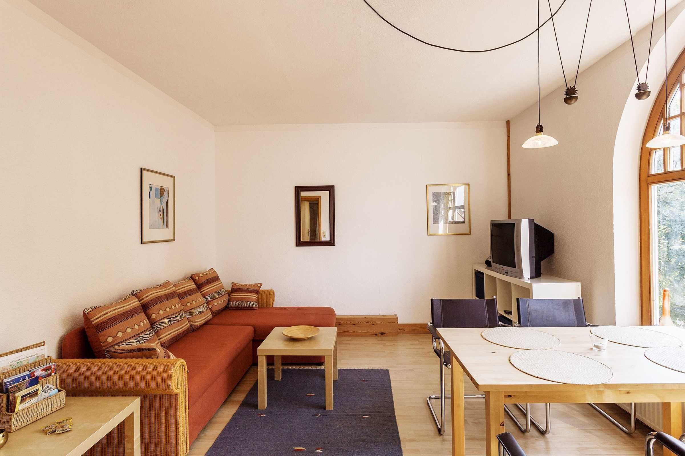 Een gezellige woonkamer met een bank, een klein tafeltje en een televisie.