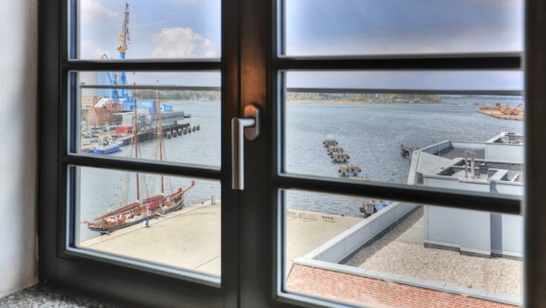 A view through a window with multiple panes, each showing different parts of a harbor with boats and industrial structures. - Ohlerich storage app. 41 - Ohlerich Speicher App. 41 (Wismar)