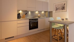 A modern kitchen with white cabinets, a built-in oven, and a dining area with a table and chairs. - Ohlerich storage app. 41 - Ohlerich Speicher App. 41 (Wismar)