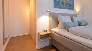 A bedroom with a bed, bedside tables, a painting, and a nightstand. - Ohlerich storage app. 41 - Ohlerich Speicher App. 41 (Wismar)