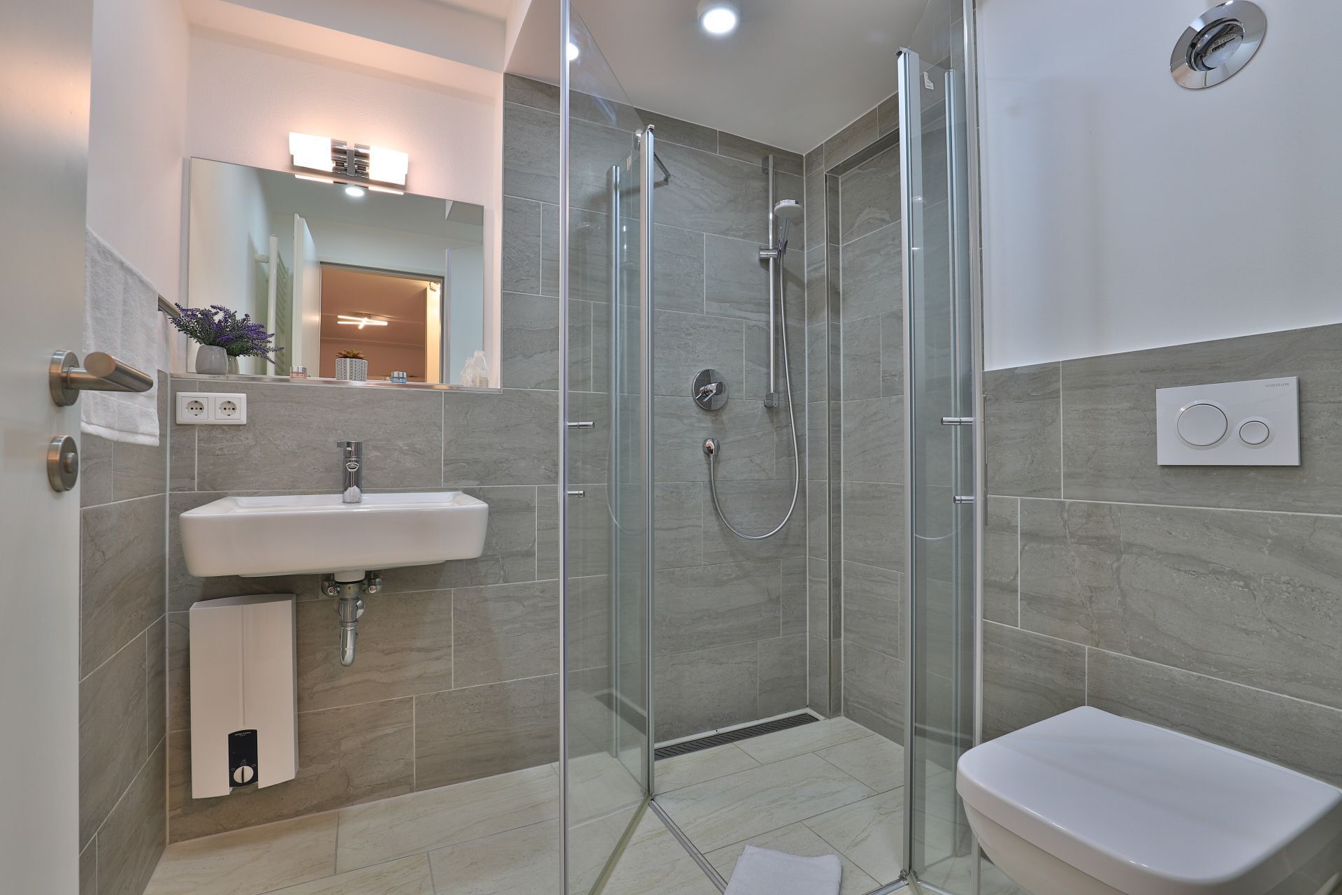 A modern bathroom with a glass-enclosed shower, a sink, and a toilet.
