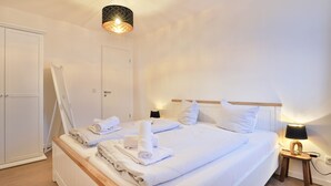 Une chambre d’hôtel avec un lit bien fait, une table de chevet avec une lampe et une armoire.
