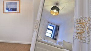 Une chambre à coucher avec un lit, une fenêtre et un luminaire au plafond.