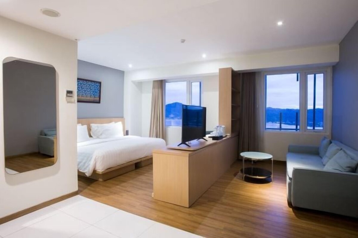 Una habitación de hotel con una cama, un escritorio, un sofá y un televisor.