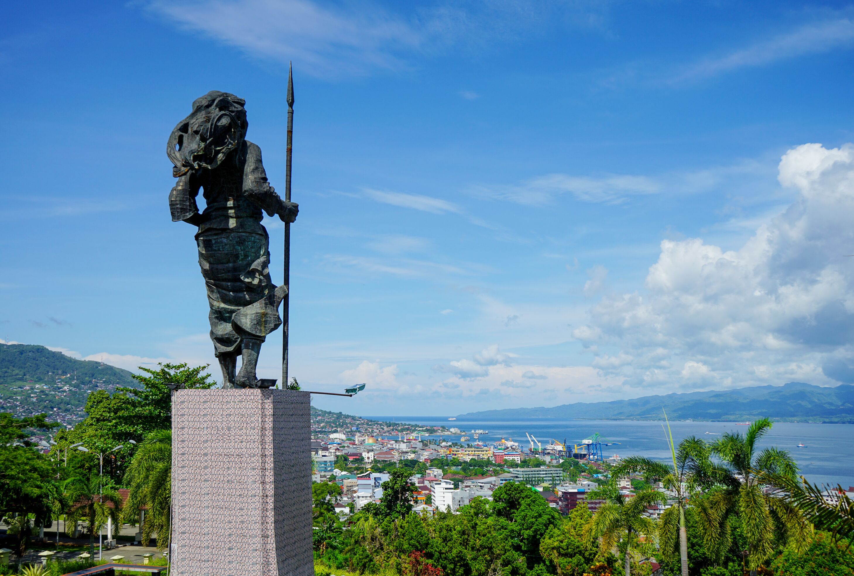 Una estatua sobre un pedestal con vistas a una ciudad costera.