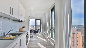 A modern kitchen with a long countertop, a sink, and a window with curtains.