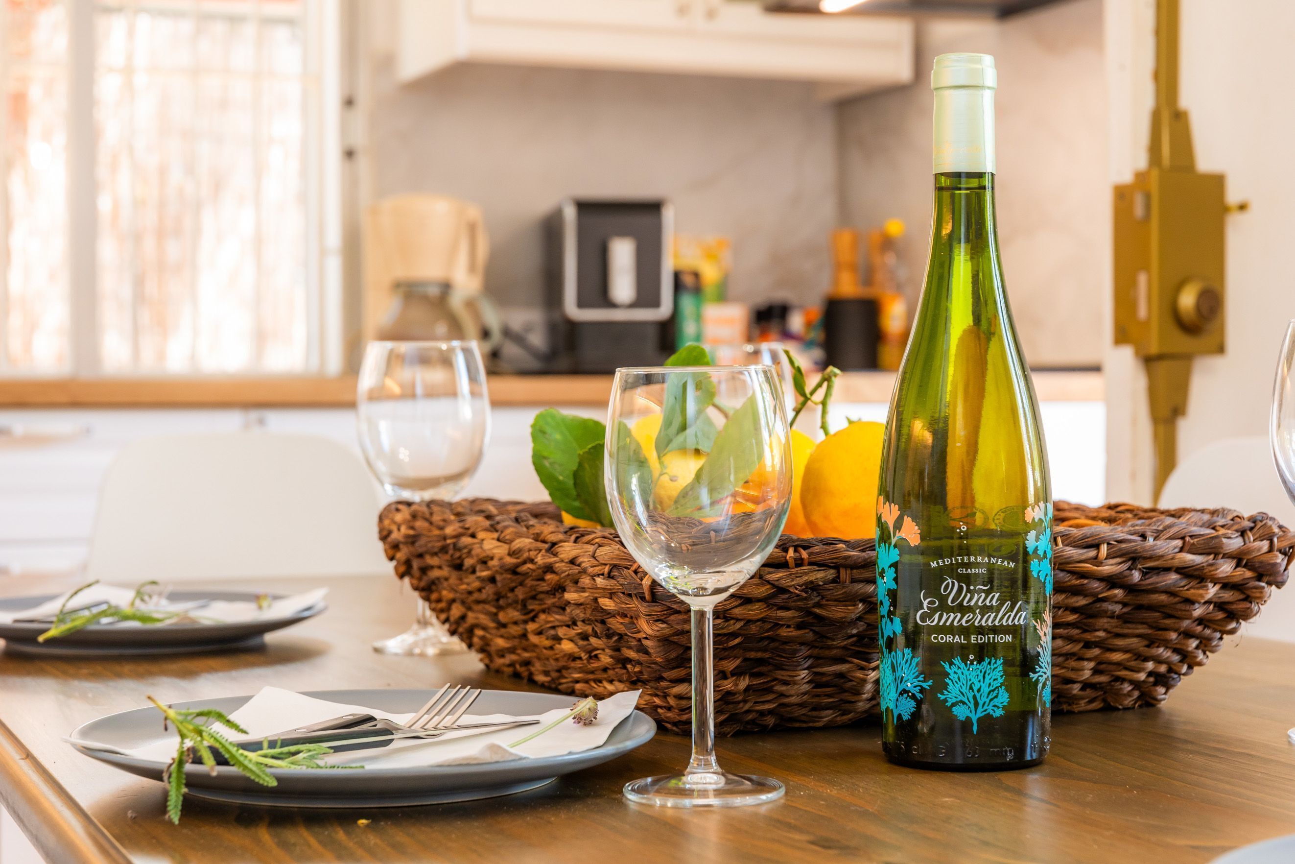 A dining table with plates, cutlery, a wine bottle, and glasses.