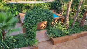 A landscaped garden area with a wooden deck, a small pool, and various tropical plants.